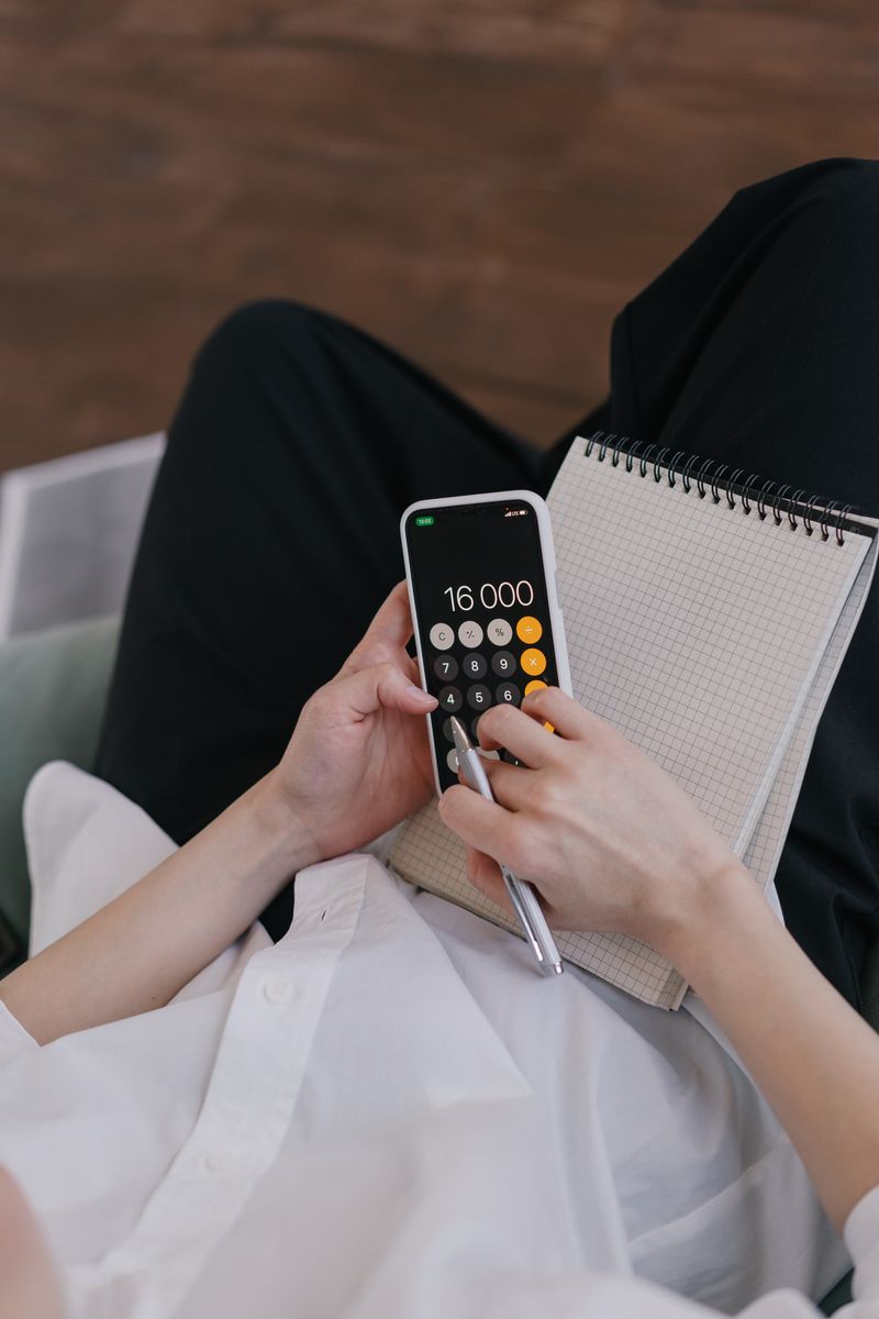 Two people reviewing shared household expenses on a tablet at a kitchen table.